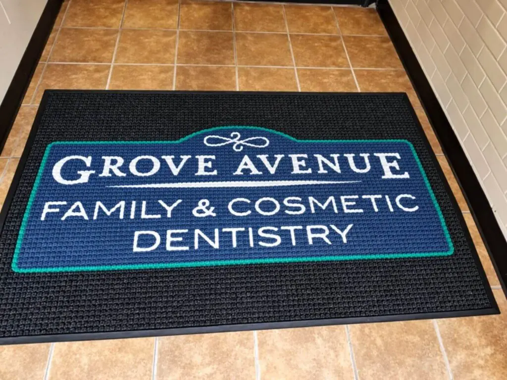 Grove Avenue Family and Cosmetic Dentistry custom WaterHog Impressions HD entrance mat with blue and teal logo installed at office vestibule